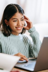 Jeune femme qui sourie devant son ordinateur