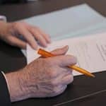 Un personne s'apprête à signer un papier avec un stylo dans la main